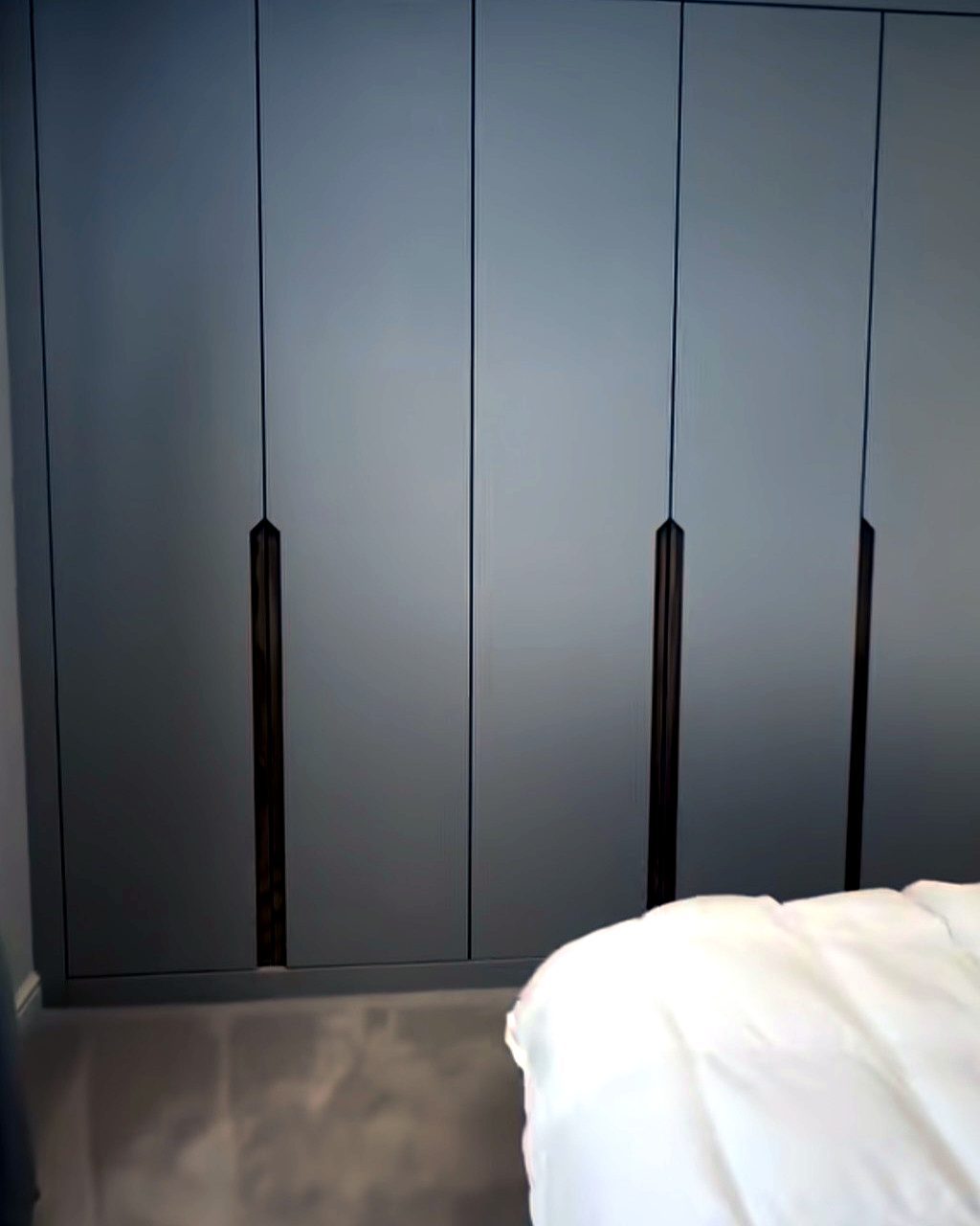 Close-up detail of bespoke taupe fitted wardrobe doors with inset timber handle detailing, installed by BFK