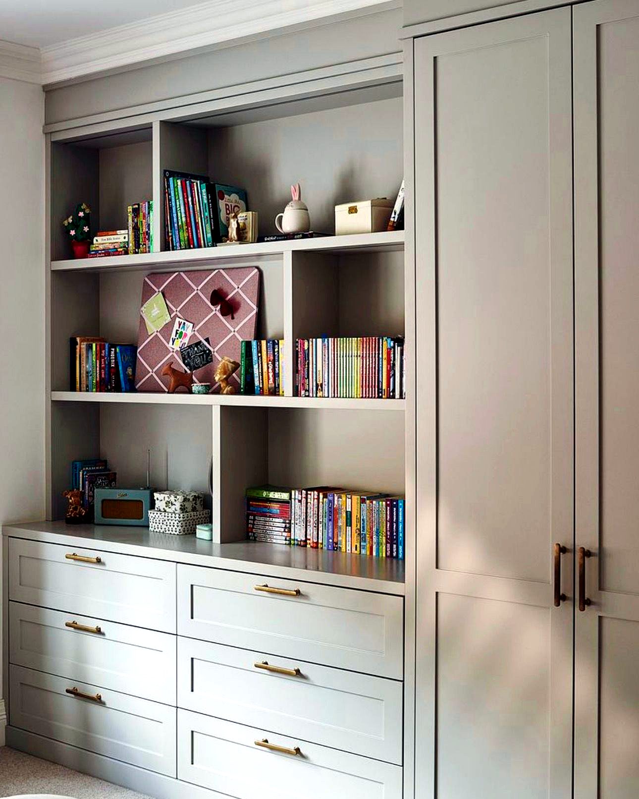 Fitted bedroom storage in soft grey with open shelving, deep drawers and brass bar handles
