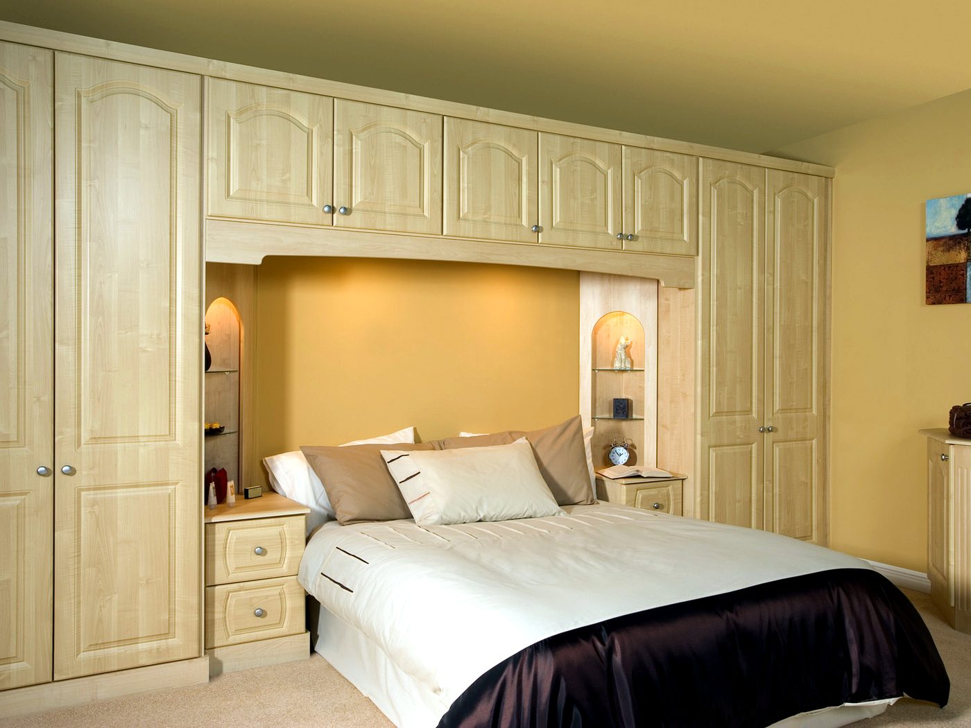 Maple woodgrain overbed wardrobe suite with arched panel doors, bridging cupboards and lit display niches