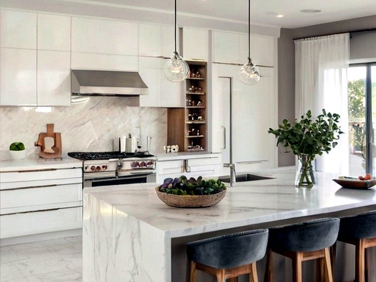 White handleless kitchen with waterfall marble island, brass trim detailing and marble splashback